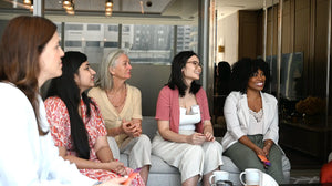 Moms sharing stories and laughing together during a Somnii Sessions event, highlighting the community aspect of Somnii's motherhood cards.
