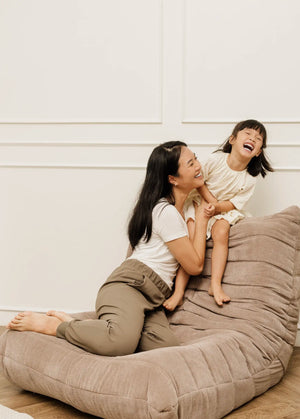 A mother and daughter laughing and playing together on a sofa, capturing a moment of joy and deep connection