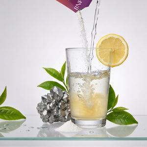 A visual representation of Somnii’s clean ingredients: magnesium ore, fresh green tea leaves, and lemon being mixed with the supplement powder in a clear glass of water.