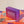 Somnii Sessions conversation card game product photo, featuring it's purple box and the tagline 'cheaper than therapy,' displayed on a pile of orange and purple prompt cards.