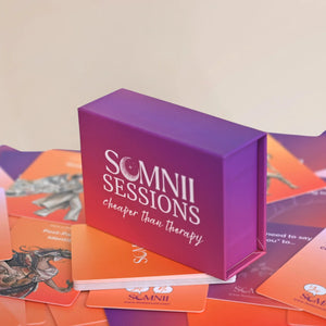 Somnii Sessions conversation card game product photo, featuring it's purple box and the tagline 'cheaper than therapy,' displayed on a pile of orange and purple prompt cards.