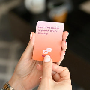 A close-up of a Somnii Sessions card held by a mom, featuring the prompt: 'Most mums secretly judge each other’s parenting,' designed to spark honest conversation.