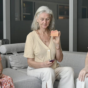 An intergenerational group of women using Somnii Sessions cards to discuss generational cycles and cognitive reframing, fostering deep emotional healing across different age groups of moms.