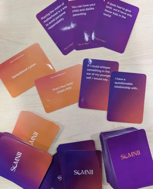 A flat lay of Somnii Sessions cards on a light wood surface, featuring prompts on 'Inner Child,' 'Generational Cycles,' and 'disliking parenting' to encourage radical honesty among moms